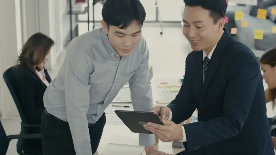 Colleagues reviewing work together on a tablet in an office