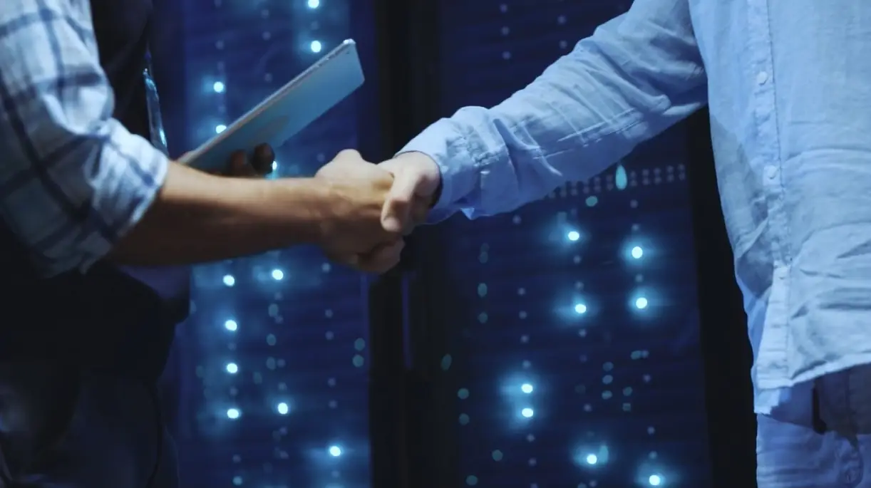 Handshake in front of illuminated server racks
