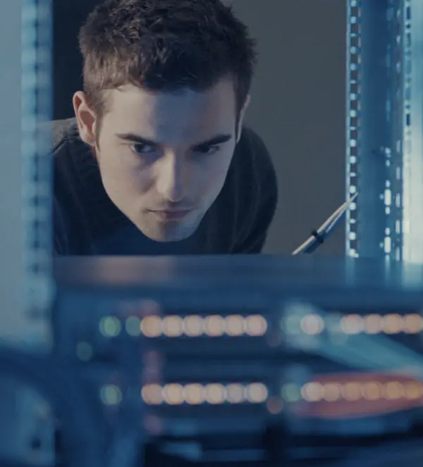 Network engineer inspecting rack-mounted switch ports
